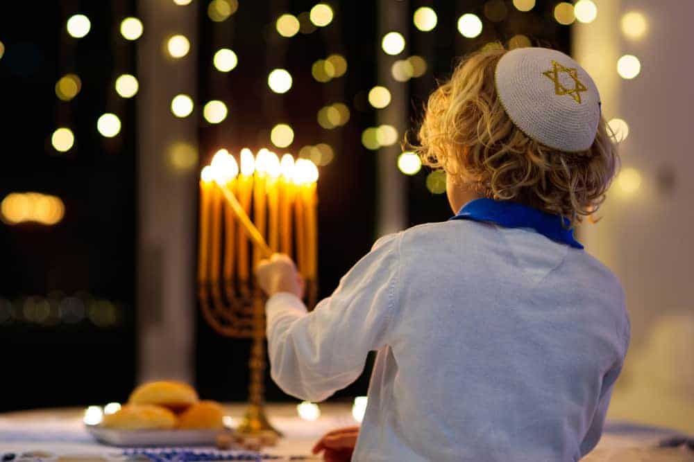 dzieci świętują chanukę zapalając świeczki na menorze
